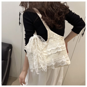 Détail du sac bandoulière en dentelle blanche avec volants étagés et un grand nœud décoratif