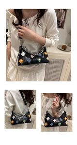 Detail of black crocodile texture baguette bag with colorful plush flowers and silver chain