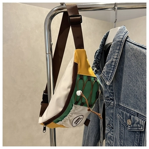 Détail du sac de poitrine en toile tricolore avec panneaux jaune et vert et cordon décoratif