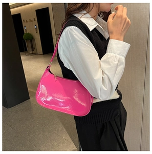 Elegante borsa sottobraccio in vernice rosa lucida vista di lato su una modella