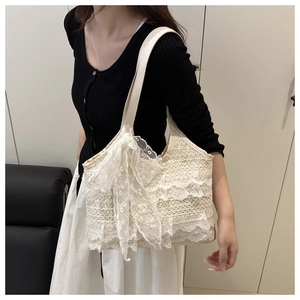 Détail des couches de dentelle et du grand nœud sur le sac de plage blanc crème