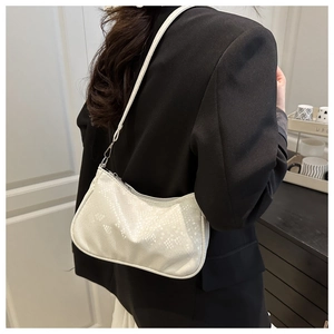 Detailed view of beige faux leather handbag with crocodile pattern on a black blazer
