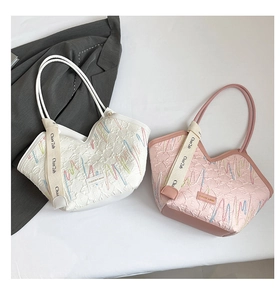 Detailed close-up of quilted tote bags in white and pink with colorful wave embroidery