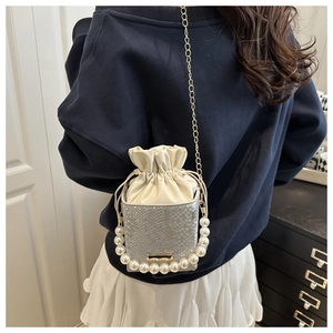 Close-up of snakeskin pattern bucket bag with white pearl handle and gold chain strap