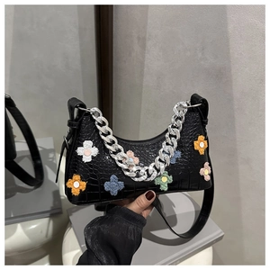 Detail of black faux crocodile hobo bag with colorful plush flower patches and silver chain