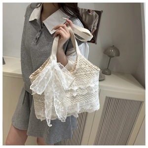 Détail d'un sac à main en dentelle crème avec froufrous en maille et grand nœud décoratif