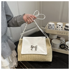 Detail of straw woven texture with a silver bow buckle on a white flap shoulder bag