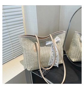 Détail d'un sac cabas en paille avec nœud en dentelle et bandoulières en cuir