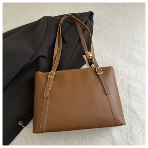 Detail of brown tote bag with contrast stitching, gold hardware and silk scarf decoration