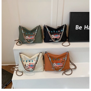 Detail view of large canvas tote bags with cat embroidery in green, black, cream and orange