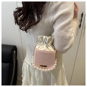 Pink snake-skin bucket bag with pearl handle and golden chain strap detail view