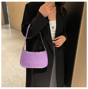 Dettaglio di una borsa sottobraccio in pelle verniciata viola lucida con zip in metallo oro