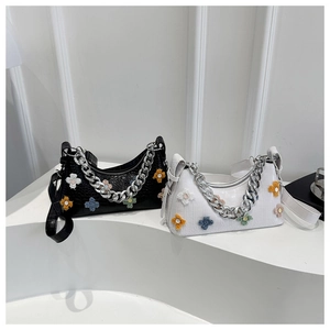 Detail of crocodile embossed baguette bag with colorful plush flowers and silver chain
