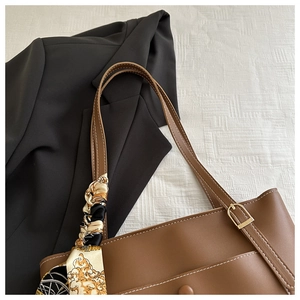 Close-up of brown PU tote bag featuring white stitching details and silk scarf accessory