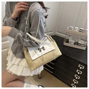 Detail of straw woven square bag with white leather flap and silver bow clasp