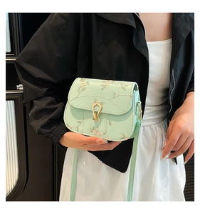 Détail du sac selle vert menthe avec broderie florale et boucle dorée en forme de U