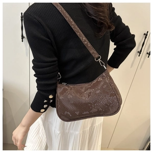 Détail d'un grand sac sous le bras en texture serpent marron porté à l'épaule