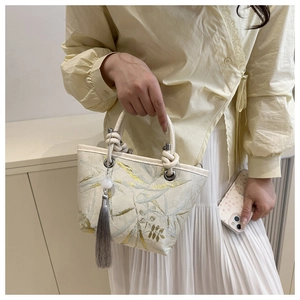 Close-up of embroidered Chinese style bucket bag with elegant silk tassel and silver hardware