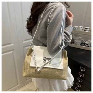 Detail of straw patchwork bag featuring a silver bow buckle and woven chain strap