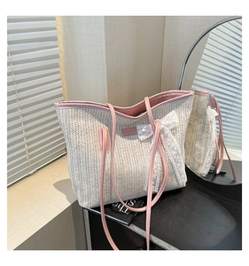 Détail d'un sac cabas en paille avec anses en cuir rose et nœud en dentelle blanche