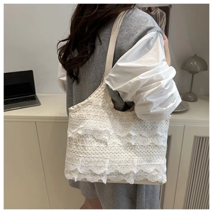 Détail d'un sac cabas en dentelle crème avec des volants ondulés et une bandoulière épurée