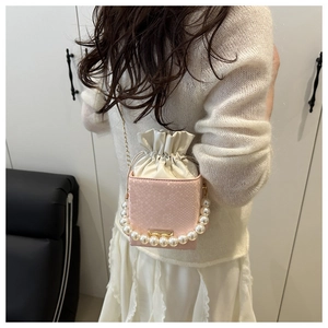 Close-up of pink snake-embossed bucket bag featuring pearl handle and gold chain strap
