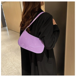 Dettaglio di una borsa sottobraccio in vernice viola lucida su un cappotto nero