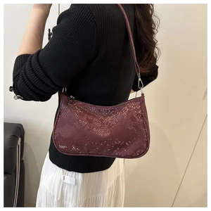 Détail de la texture serpent bordeaux d'un sac à bandoulière avec des garnitures argentées