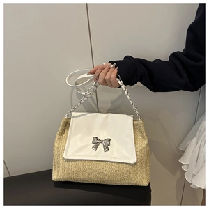 Close-up of woven straw bag with silver bow clasp and metal chain handle strap