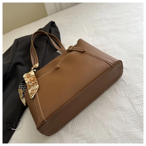 Detail of brown PU tote bag featuring white stitching, metal buckle, and silk scarf accent