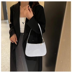 Dettaglio della borsa a spalla in pelle verniciata beige con cerniera dorata e finitura lucida