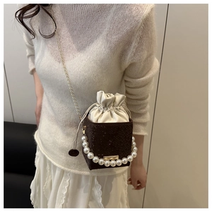 Detail of snake print mini bucket bag featuring a large pearl handle and gold chain strap