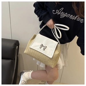 Detailed view of straw-woven crossbody bag with metallic bow buckle and chain handle