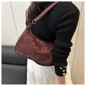 Close-up of burgundy snake-pattern baguette bag with adjustable strap and silver hardware