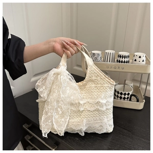 Détail d'un sac en dentelle crème avec des volants étagés et un grand nœud décoratif
