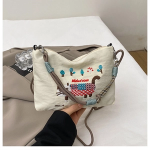 Detail of embroidered forest cat on cream canvas tote with colorful woven rope handle