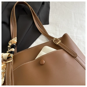 Detail of caramel brown PU leather tote bag with white stitching and silk scarf wrap