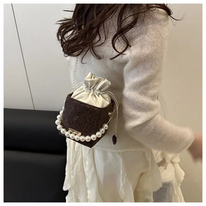 Detail view of snakeskin pattern leather bucket bag with pearl handle and gold chain