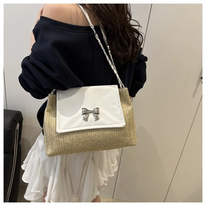 Detail of woven straw and white leather patchwork handbag with silver bow lock buckle