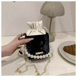 Detail of mini black snake embossed bucket bag with pearl handle and gold chain strap