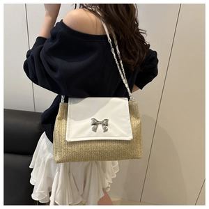 Detail of woven straw shoulder bag with silver bow clasp and chain strap on model