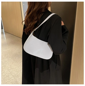 Borsa minimalista in pelle verniciata bianca indossata da una modella con blazer