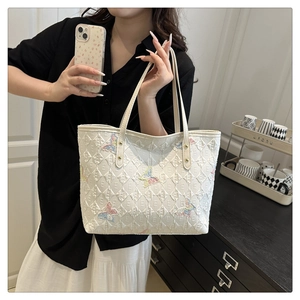 Détail de la broderie papillon colorée sur un sac cabas blanc matelassé en jacquard