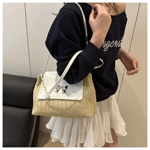 Detail of woven straw bag with leather flap and silver bow clasp shown on a model