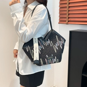 Black quilted tote bag with colorful embroidery and logo fabric strap on model