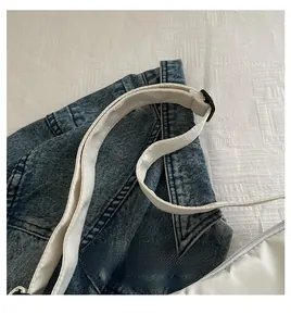 Close-up of a white canvas bag handle with black adjustable buckle on denim background