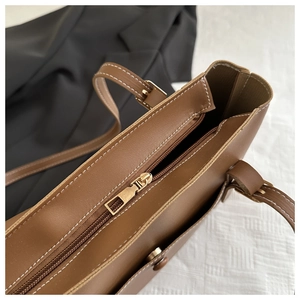 Detail view of brown PU tote bag zipper and white contrast stitching on leather material