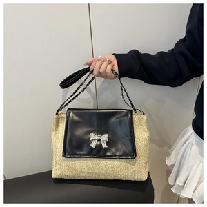 Detail of straw and black leather patchwork bag featuring a silver bow metal clasp