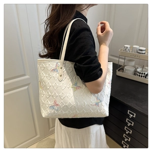 Détail du sac cabas blanc avec motif E gaufré et broderie papillon colorée