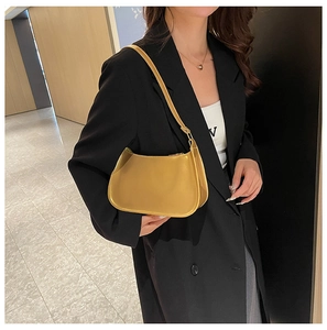 Elegante borsa hobo giallo senape mostrata come dettaglio a tracolla su abito nero